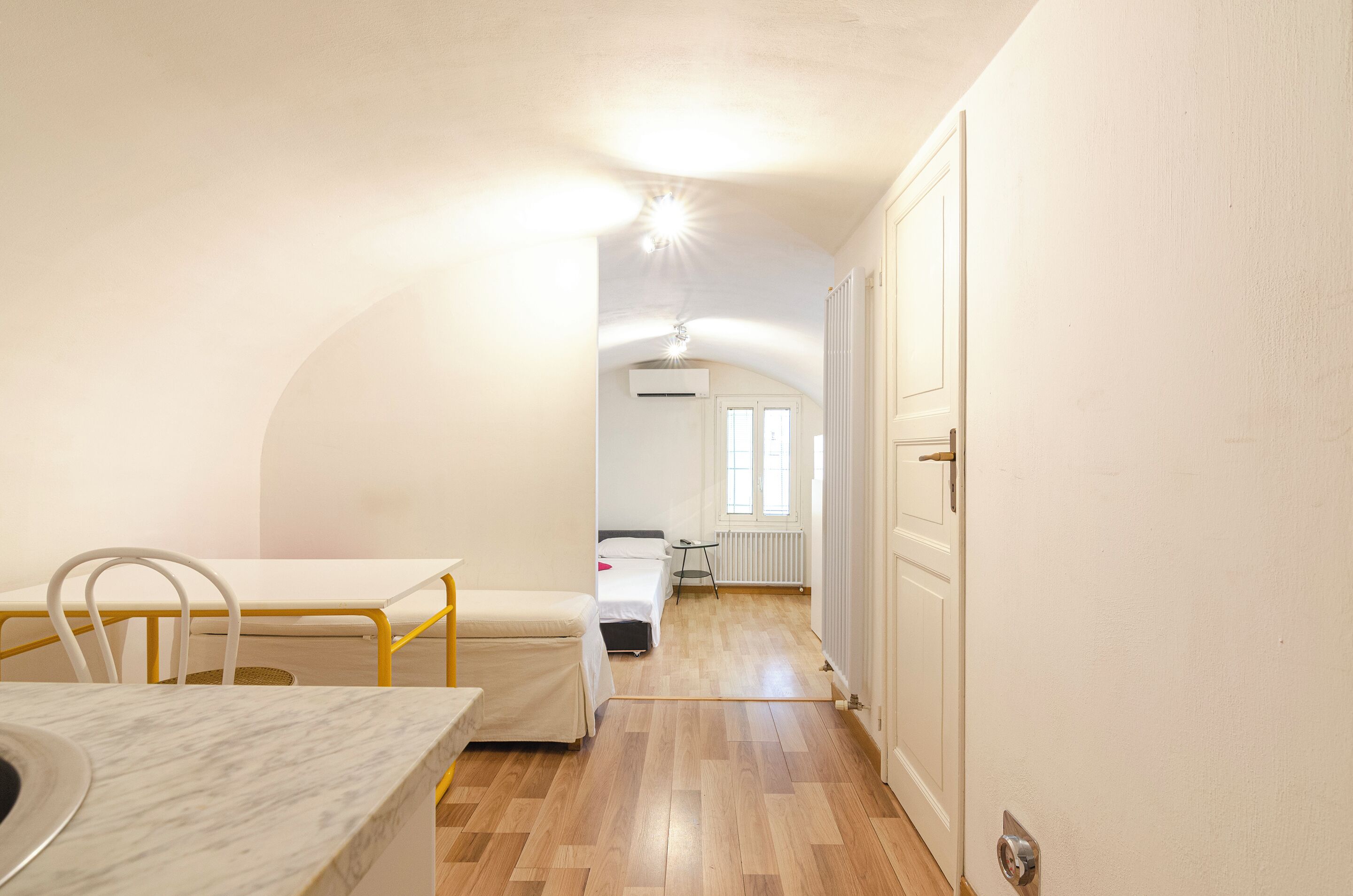 A narrow hallway with a bed, a small table, and a radiator.