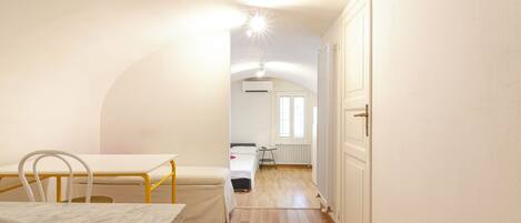 A narrow hallway with a bed, a small table, and a radiator.