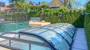 Zona de piscina con cerramiento de vidrio y vistas a un barrio residencial.