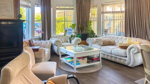 Un salón amplio con un conjunto de sofá blanco, una mesa de centro y un televisor sobre un mueble.