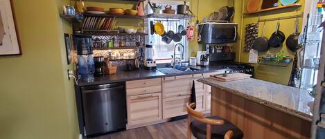 A compact kitchen with wooden cabinets, a built-in microwave, and a ceiling fan.