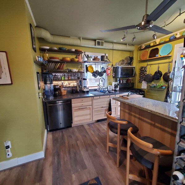 A compact kitchen with wooden cabinets, a built-in microwave, and a ceiling fan.