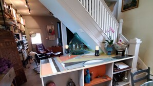 A multi-level living space with a staircase, wooden flooring, and various decorative items including figurines and a glass vase. - 10 minutes walk 2 "Everything Frederick", OSP, Sports Events, Sleeps up to 8 (Frederick)