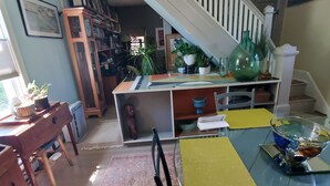 A spacious living area with a staircase leading to an upper floor, a dining table with chairs, a coffee table, and a patterned rug. - 10 minutes walk 2 "Everything Frederick", OSP, Sports Events, Sleeps up to 8 (Frederick)