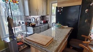 A kitchen with a granite countertop, wooden cabinets, a refrigerator, and a window with a stained glass bird decoration. - 10 minutes walk 2 "Everything Frederick", OSP, Sports Events, Sleeps up to 8 (Frederick)