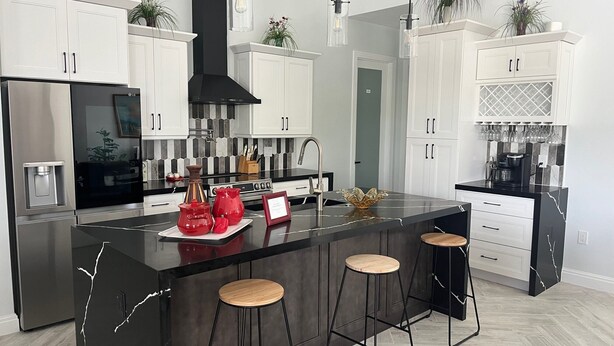 A modern kitchen with a large island, stainless steel appliances, white cabinetry, and black accents. - Sueños Villa (Cape Coral)