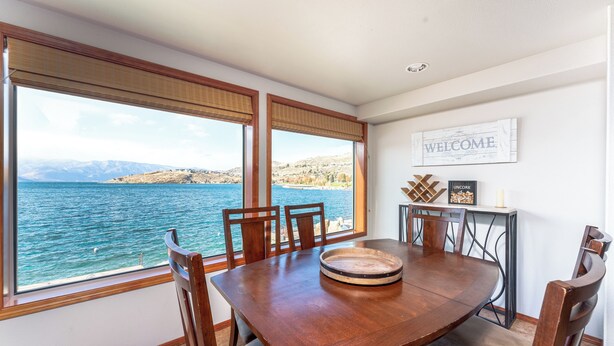 A dining area with a large table, chairs, and a view of the sea. - GrandView 303 -2 Bedroom Waterfront condo (Chelan)