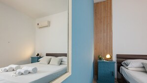 Una habitación de hotel con cama, mesita de noche, espejo y armario.
