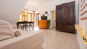 Una sala de estar con un sofá, un armario de madera, un televisor y una zona de comedor con sillas y una mesa.
