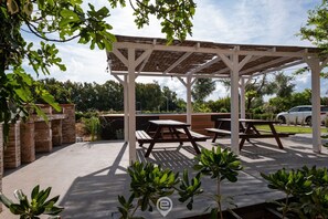 A covered outdoor area with picnic tables and potted plants.
