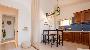 A modern kitchen with wooden cabinets, a bar stool, and a hanging light fixture.