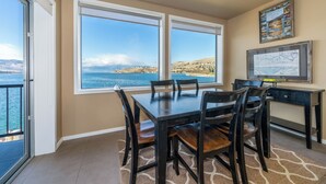 Un comedor con una mesa y sillas, vistas al mar y un mapa enmarcado en la pared.