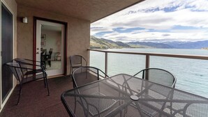A balcony with a table and chairs, a door, and a view of a lake and mountains. - Grandview 541 Executive Waterfront condo (Chelan)