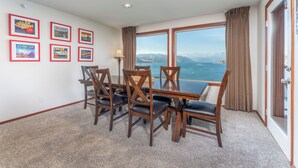 A dining area with a table and chairs, framed pictures on the wall, and a view of the sea. - Grandview 541 Executive Waterfront condo (Chelan)