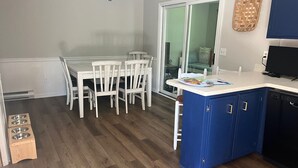 A kitchen with a white dining table, blue cabinets, and a black TV. - Charming pet-friendly, beach home near Bethany Beach- great local attractions.  (Ocean View)