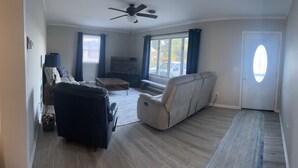 A living room with a ceiling fan, a sofa, a recliner, a TV, and a window with curtains. - Charming pet-friendly, beach home near Bethany Beach- great local attractions.  (Ocean View)