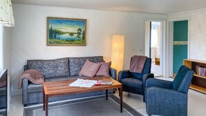 Ein Wohnzimmer mit Sofa, Sessel, Couchtisch und einem Bild an der Wand.