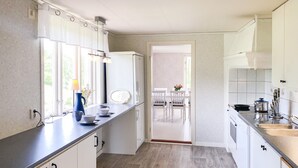 Eine moderne Küche mit weißen Schränken, einer schwarzen Arbeitsplatte und Blick in einen Essbereich.