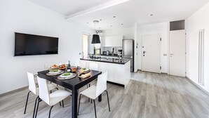 A modern kitchen with white cabinetry, a black pendant light, and a dining area with a black table and white chairs. - Il Quadrifoglio D4 Apartment by Wonderful Italy (Sirmione)