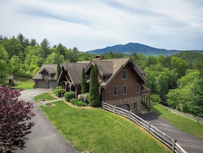 Un grand chalet rustique composé de plusieurs bâtiments, doté de fondations en pierre et d’une terrasse en bois.