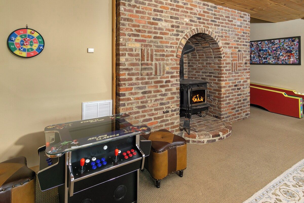 Una habitación con chimenea de ladrillo, un dardo y una mesa de futbolín.