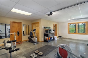 Ein Fitnessraum mit Trainingsgeräten, Laufband und einer Gewichtbank.