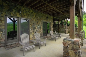 Un espace extérieur aménagé, abrité et doté de chaises Adirondack, de murs en pierre et offrant une vue sur le paysage.