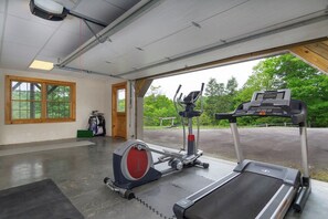 Une salle de sport équipée d’un tapis de course, d’un vélo elliptique et d’un vélo d’appartement, avec de grandes fenêtres et une vue sur l’extérieur.
