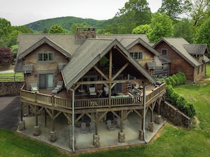 Ein mehrstöckiges Blockhaus mit überdachter Terrasse und Sitzgelegenheiten im Freien.