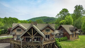 Une grande cabane en rondins dotée d’une véranda qui fait le tour de la maison, de plusieurs chambres et de fondations en pierre.
