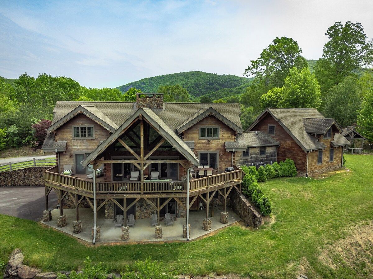 A lodge with a large porch, multiple rooms, and a stone foundation.