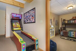 Une pièce avec un flipper, un mur décoré d’un collage, un lit superposé et une armoire.