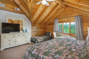 Ein Schlafzimmer mit Holzboden, einem Bett mit einem gemusterten Quilz, einem Schminktisch mit Spiegel und einem Fernseher.