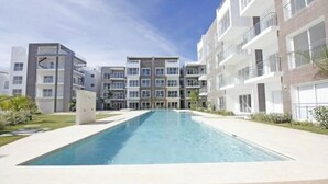 A modern apartment building with a central swimming pool, multiple balconies, and a clean, landscaped environment. - Exquisite 2-Bed/2-Bath Retreat by Hard Rock Hotel (Bavaro)