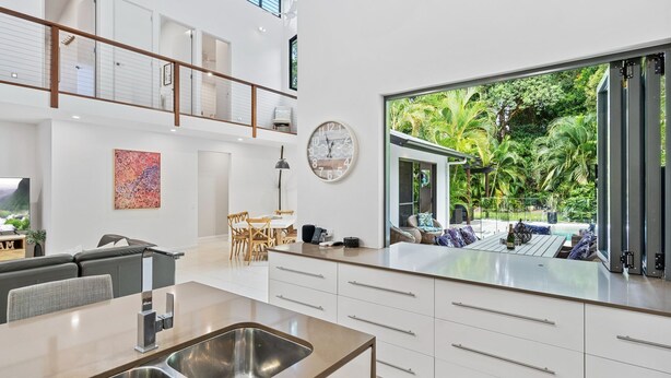 Una cocina moderna con un amplio ventanal que da a un jardín tropical.