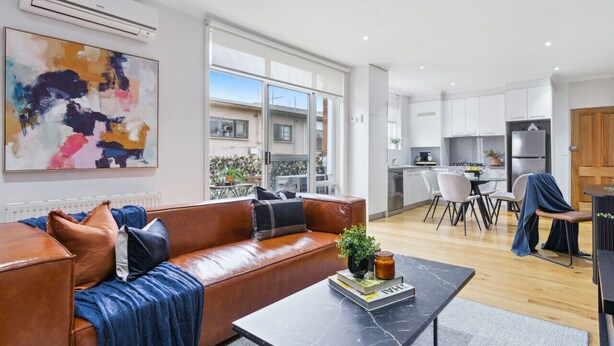 A modern living room with a leather sofa, a coffee table, and a large abstract painting.