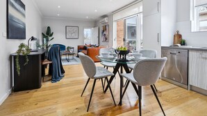 A modern kitchen with a dishwasher, dining table with chairs, and a living area with a sofa and coffee table.