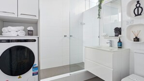 Ein modernes Badezimmer mit einer gläsernen Duschkabine, einem weißen Waschbecken und einer Toilette.