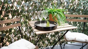 A wooden table with two glasses on a tray, surrounded by a lattice fence with green foliage.