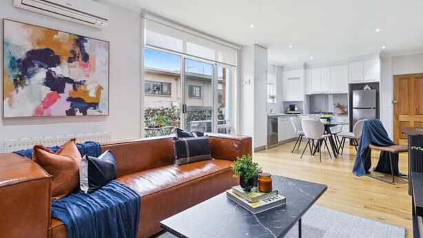 Ein modernes Wohnzimmer mit einer Ledersofa, einem Couchtisch und einem großen abstrakten Gemälde.