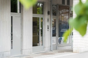 Entrada de un edificio con puerta de cristal marcada con el número 26, un cartel visible y parte de un cartel con un elefante azul.
