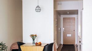 A modern living room with a wooden dining table, black chairs, a white sofa, and a small side table with candles. - Vapari - Tampere Soccer Stadium by Come in! (Tampere)
