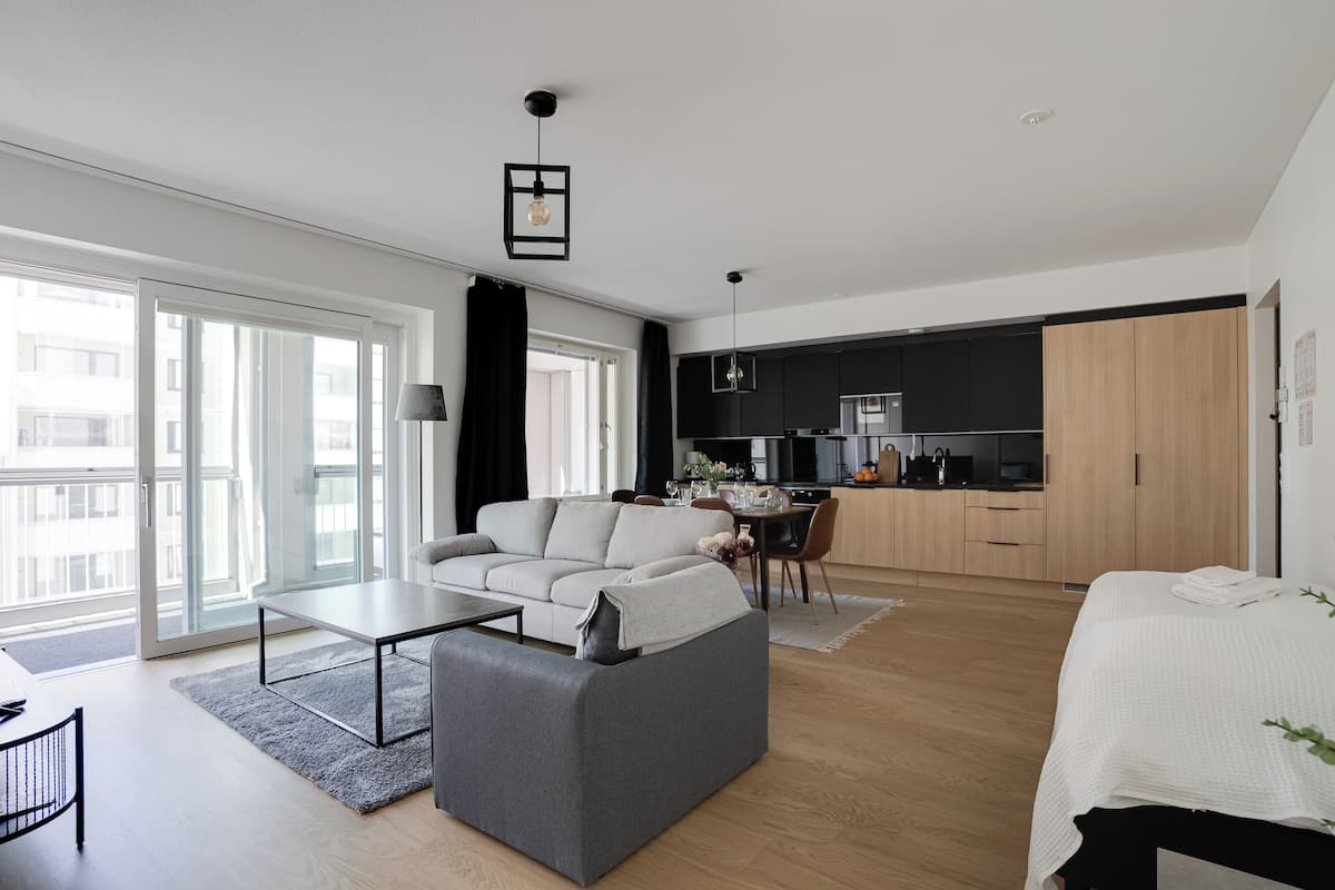 Eine moderne Wohnung mit Wohnbereich, Essbereich und Küche. Sie verfügt über ein Sofa, einen Esstisch und eine Küchenarbeitsplatte.