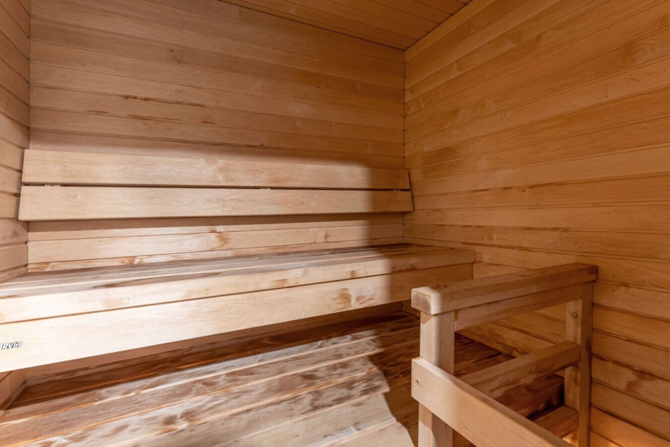 A sauna with wooden benches and a wooden railing.