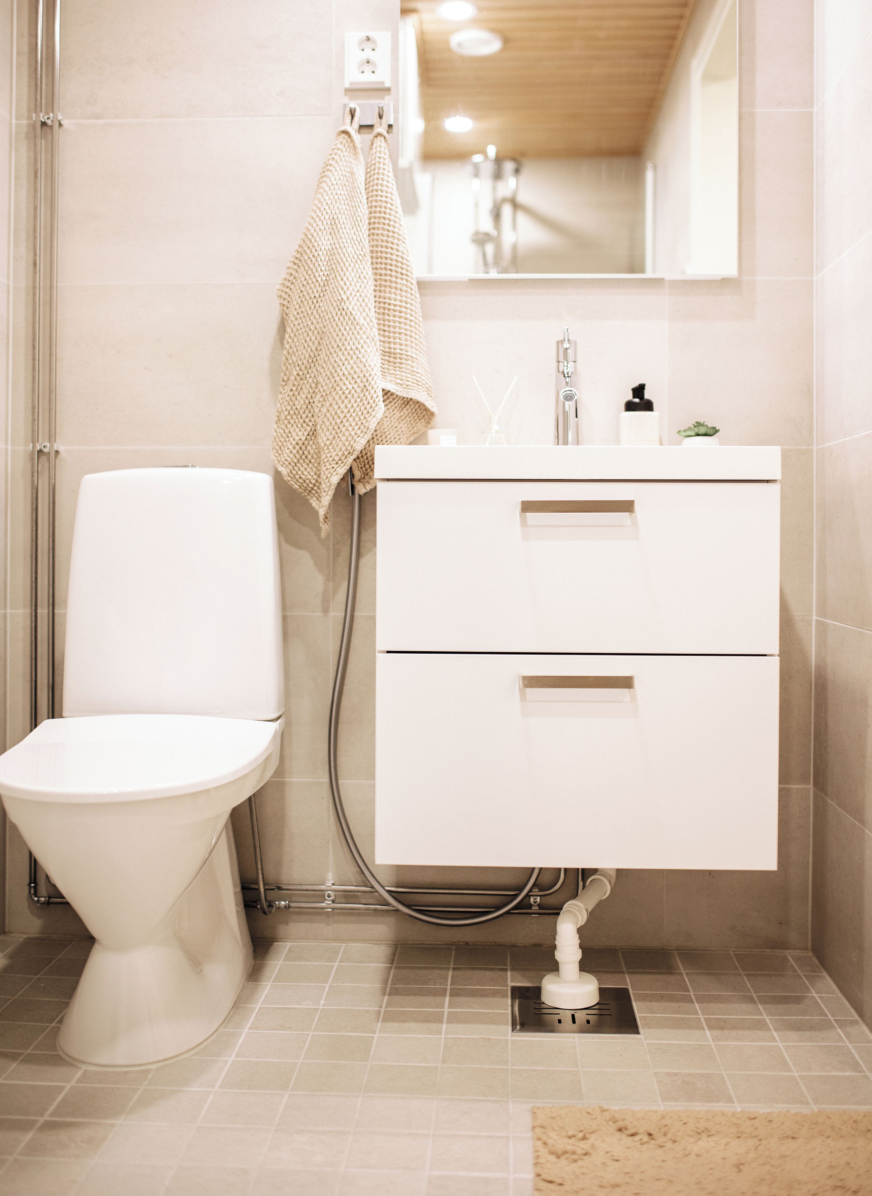 A modern bathroom with a white toilet, a sink with a mirror above it, and a towel hanging on a rack.