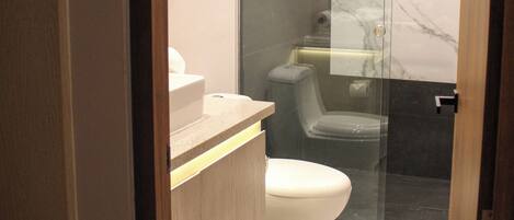 A modern bathroom with a glass-enclosed shower, a toilet, and a vanity with a mirror.