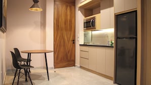 Een kleine keuken met een magnetron, koelkast, en een eethoekje met stoelen en een tafel.