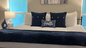 A bedroom with a bed, a bedside table, a lamp, a checkered rug, and a painting on the wall. - Neeley"s Country Suite
 (Walland)