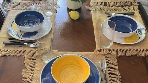 A dining table set with blue and yellow plates, white flowers, and a vase. - Neeley"s Country Suite
 (Walland)