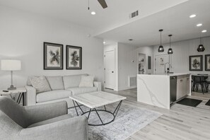 A modern living room with a sofa, coffee table, and a dining area with chairs.